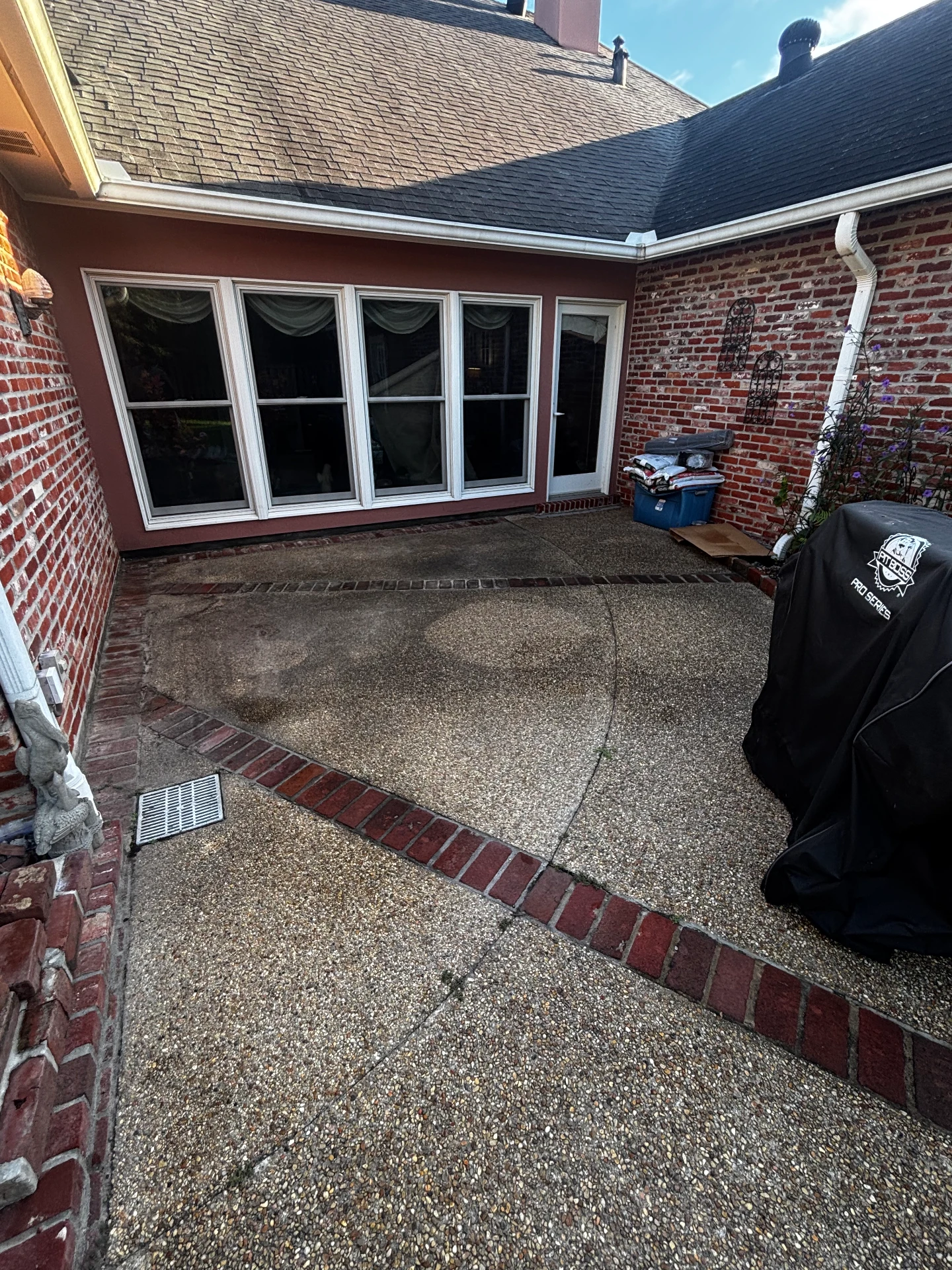 Patio with exposed aggregate concrete and brick borders before cleaning