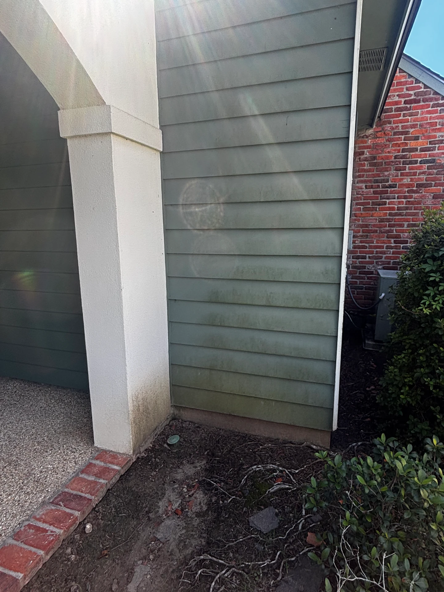 House siding beside the brick wall before cleaning